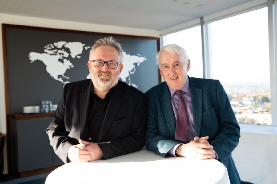 photograph of Peter Harrington and Paul Healy, leaning on table, looking straight at camera lens, smiling